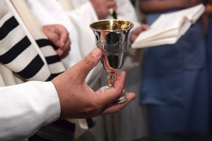 Rabbi holds silver kiddish cup with wine